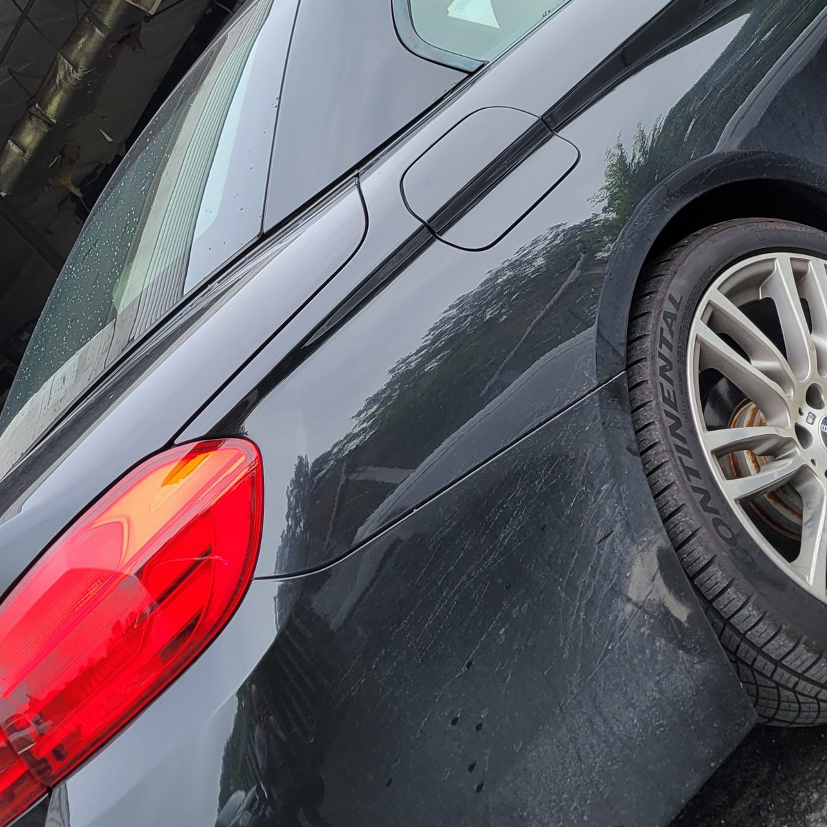 Dull, hazy black paint on a BMW 435i rear quarter panel before correction