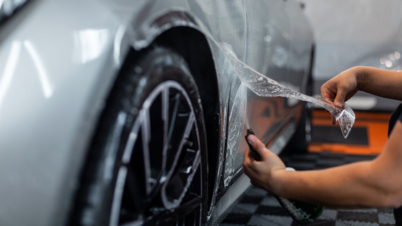 Installer applying clear paint protection film to a vehicle panel